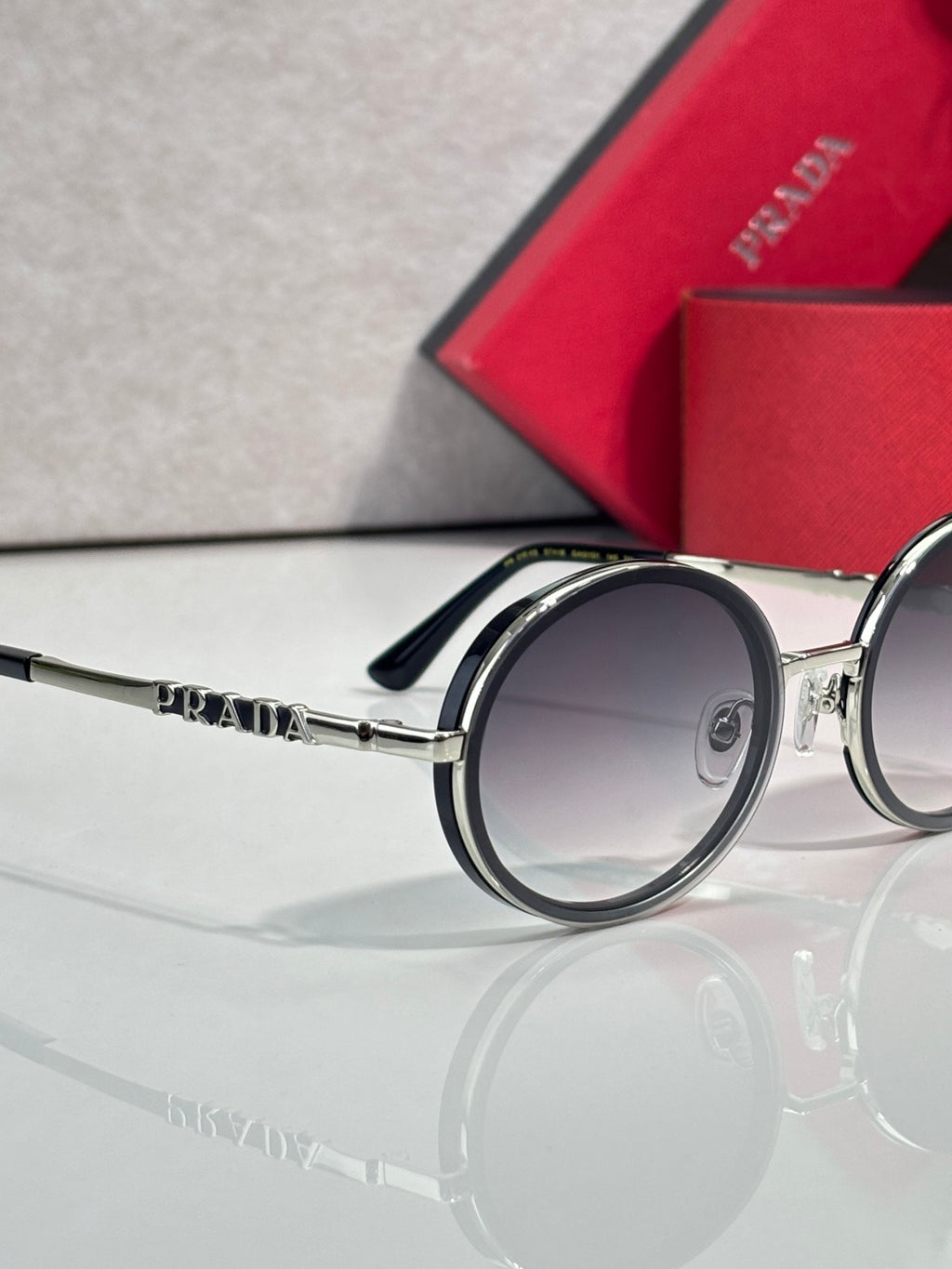 Prada round eyeglasses, dark lens side view, silver arm with PRADA logo