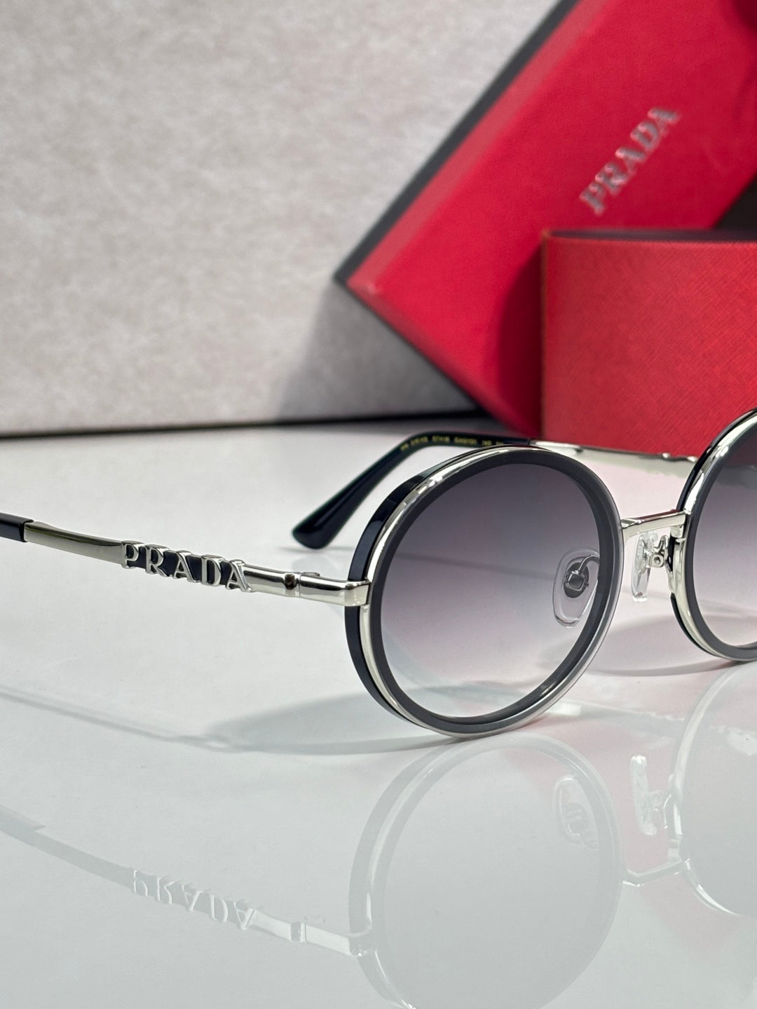 Prada round eyeglasses, dark lens side view, silver arm with PRADA logo