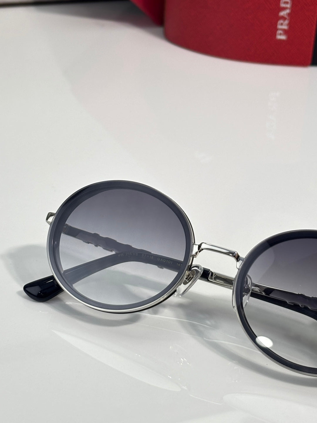 Prada round eyeglasses angled view, dark lenses, silver bridge