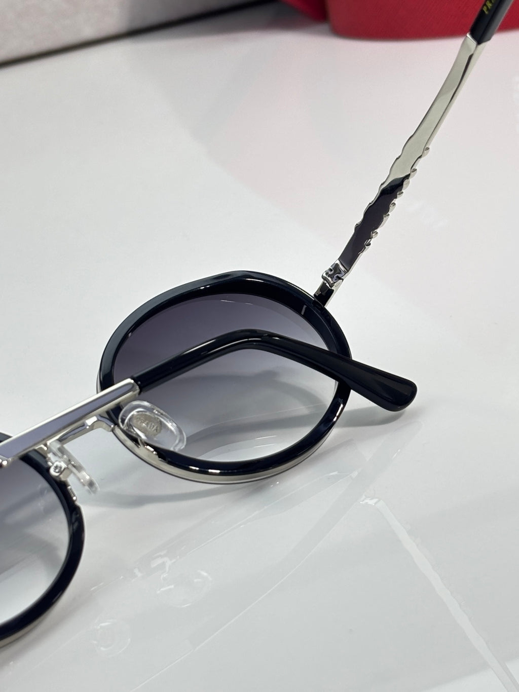 Prada round eyeglasses close-up, dark lens and curved black temple