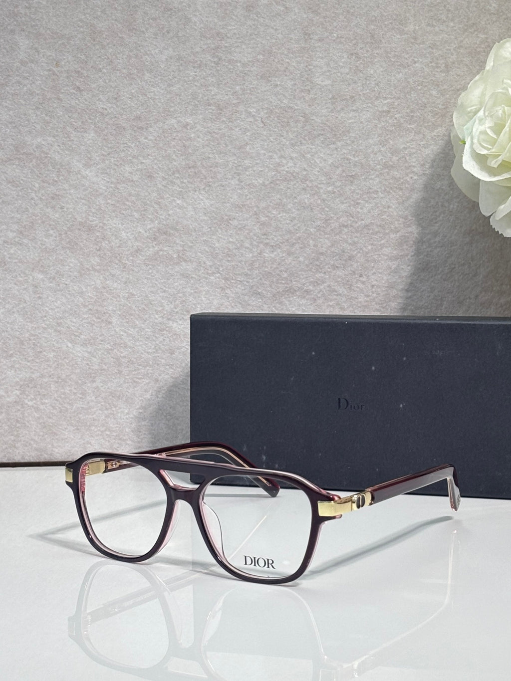Rectangular eyeglasses with dark red frame, clear lenses, and Dior logo on bridge