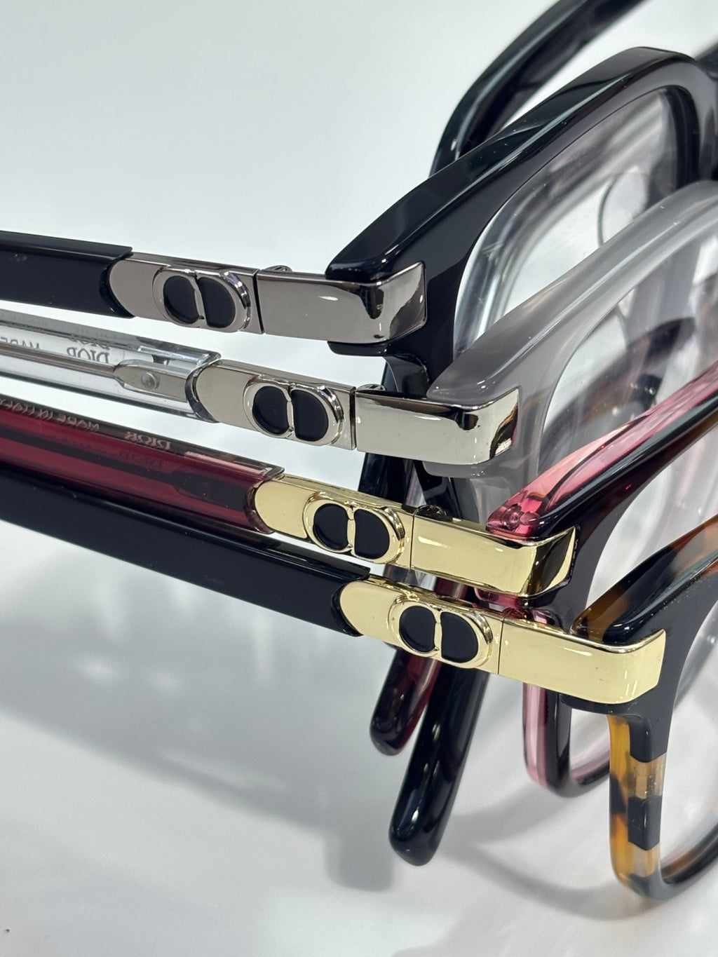 Stacked Dior eyeglasses close-up showing black frames and gold-tone metal details
