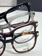 Close-up of Dior eyeglasses frames in black, white, and tortoiseshell with clear lenses