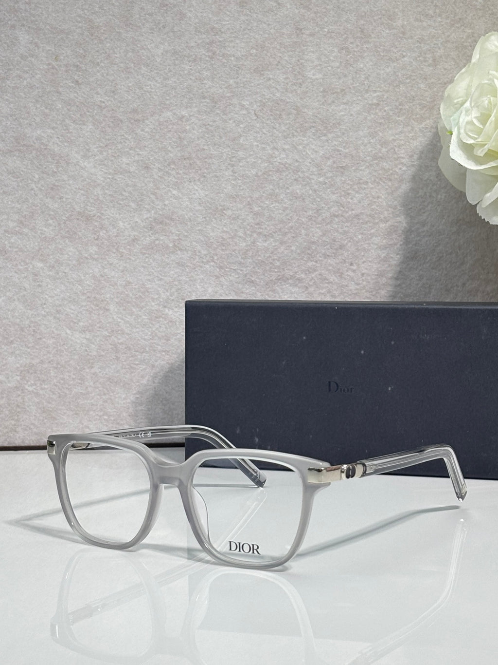 Dior eyeglasses with clear light-gray frames and dark logo on the front center.