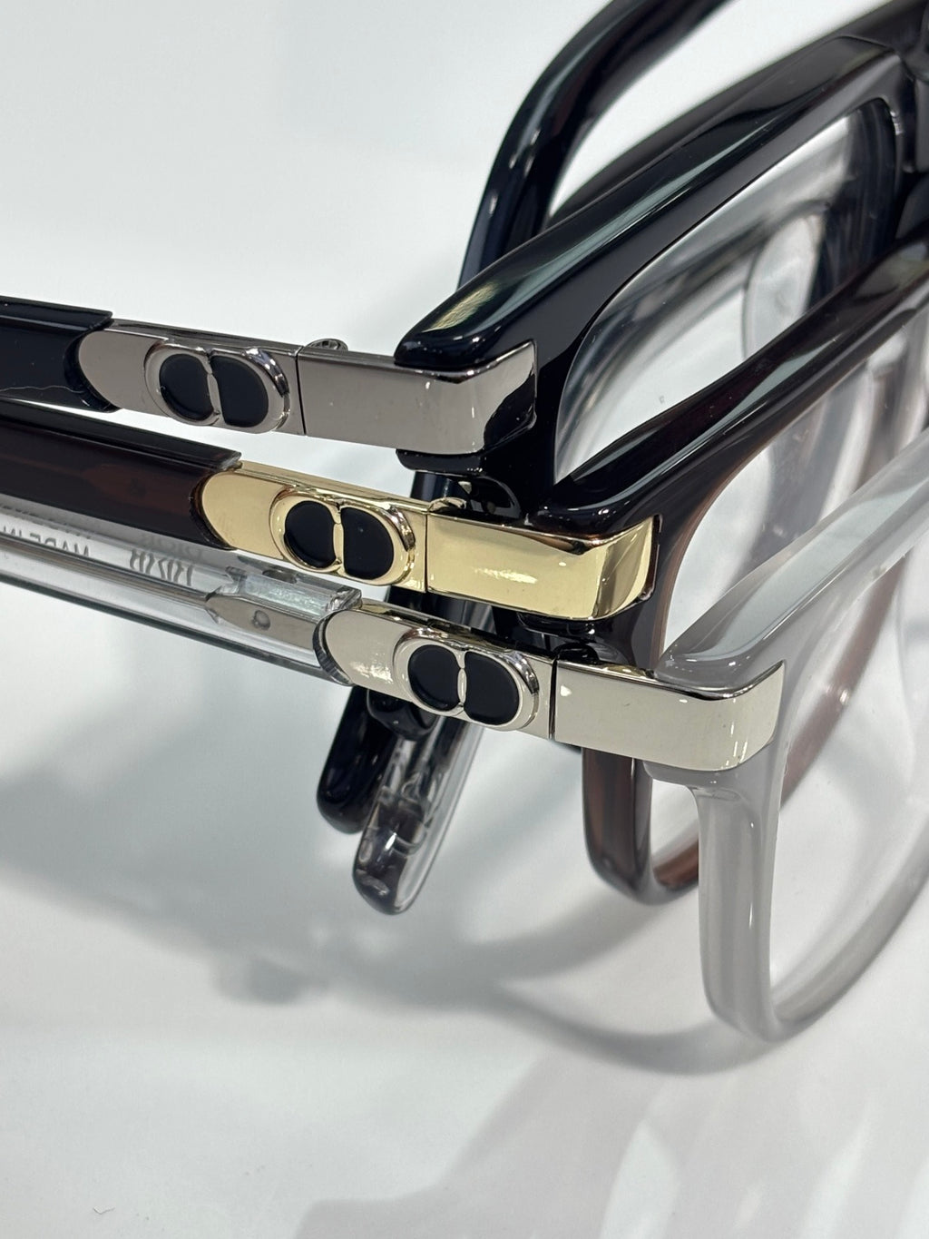 Dior glasses close-up: black and gold temples with oval logo medallions near the hinge.