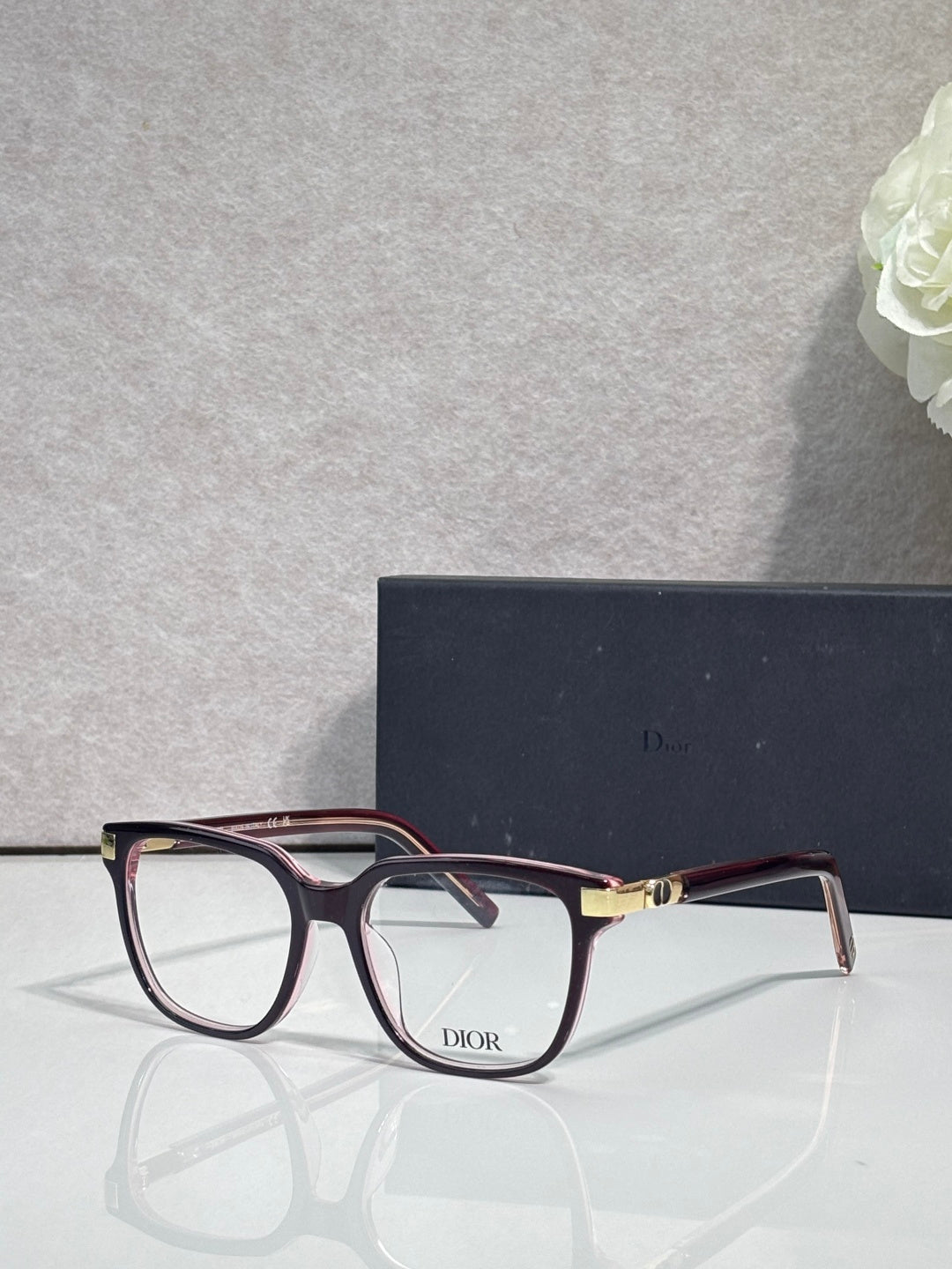 Dior eyeglasses with burgundy rectangular frames and gold-toned bridge hardware.
