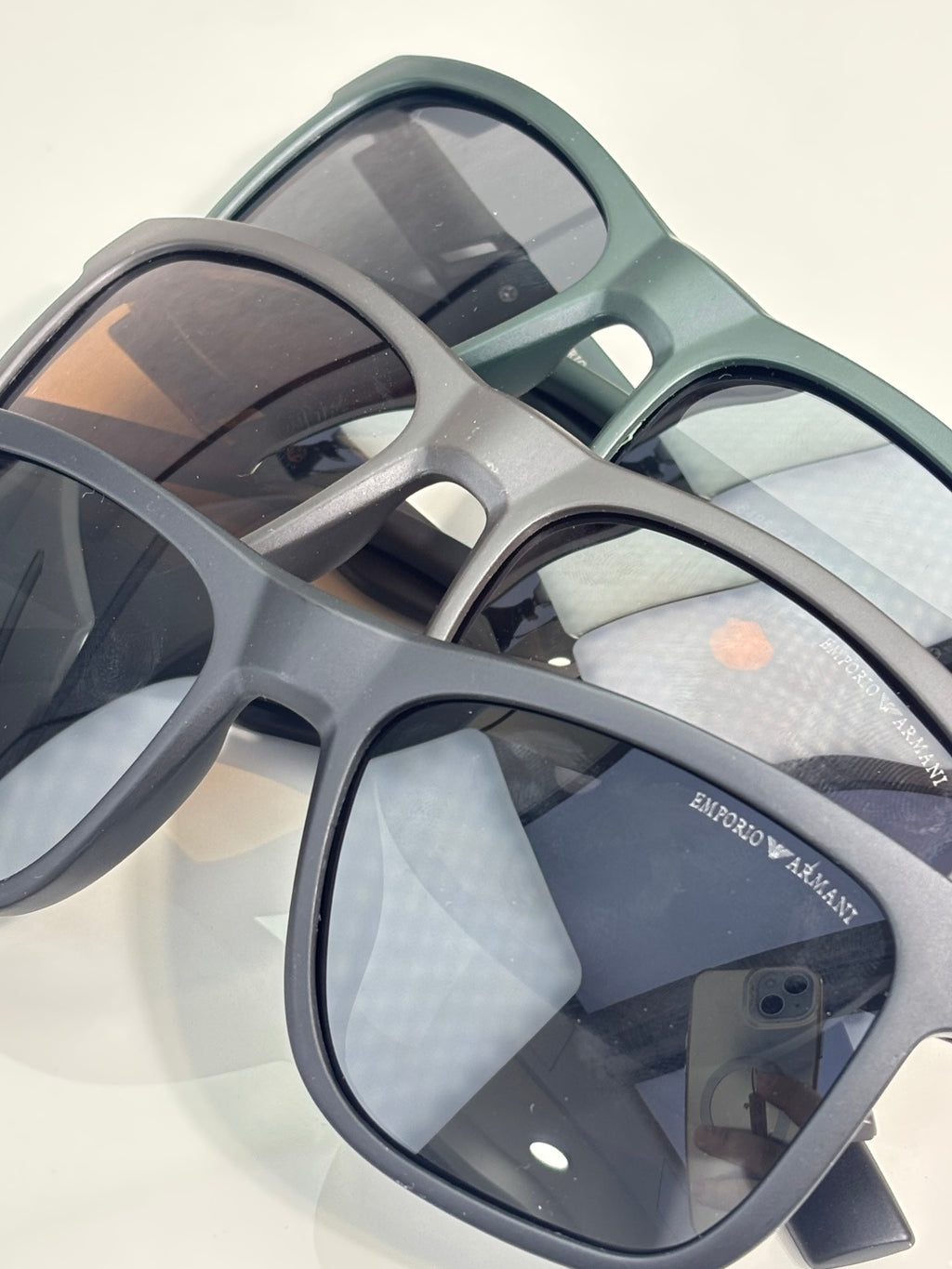 Eyeglasses close-up with light gray frames and dark lenses, logo on temple