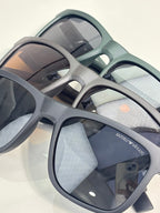 Eyeglasses close-up with light gray frames and dark lenses, logo on temple