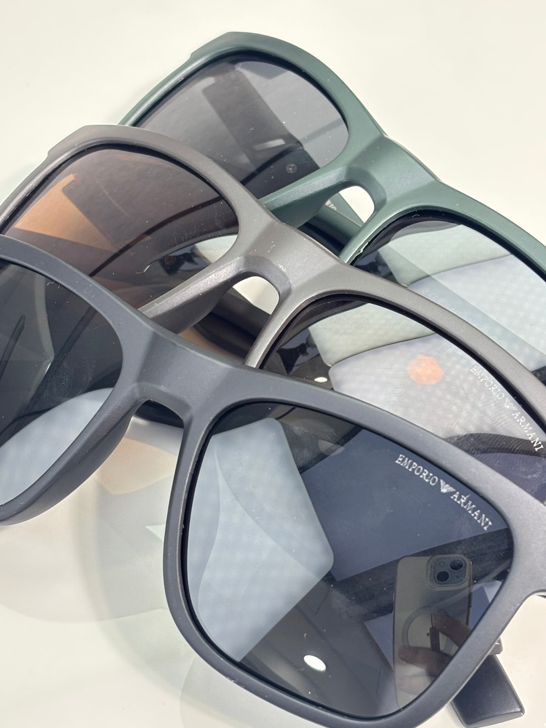 Eyeglasses close-up with light gray frames and dark lenses, logo on temple