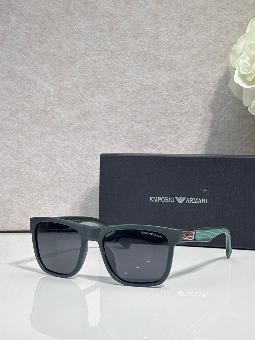 Designer glasses with gray frames, dark lenses, and green temple accents