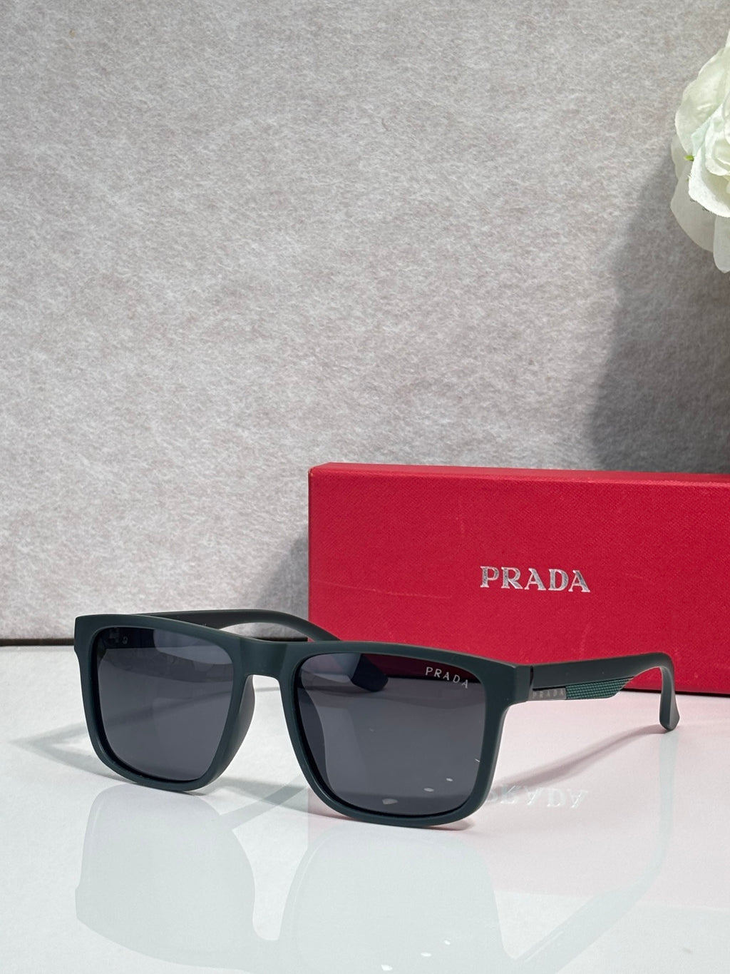Prada sunglasses with dark navy frames and smoky lenses, red temple detail
