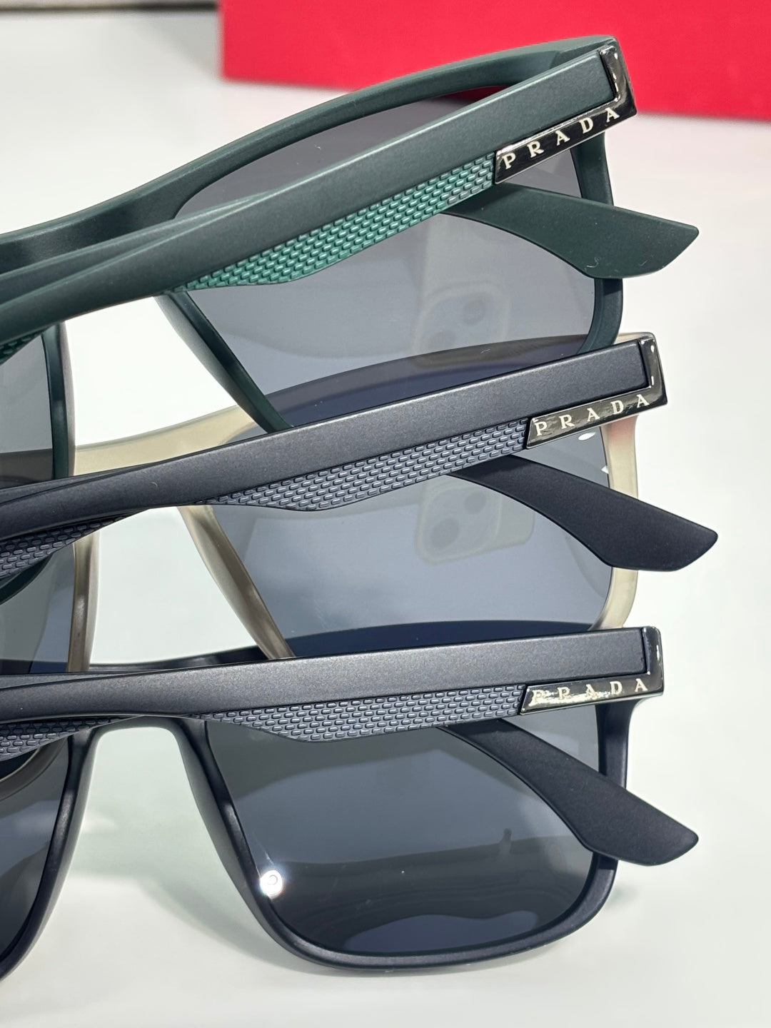 Prada sunglasses temple close-up with teal texture and engraved Prada logo on arms