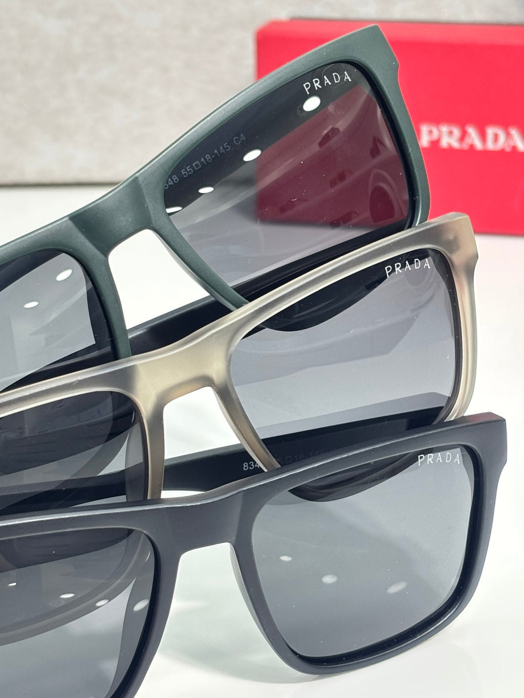 Prada sunglasses side view with dark green frame, tinted lenses, and teal textured temple