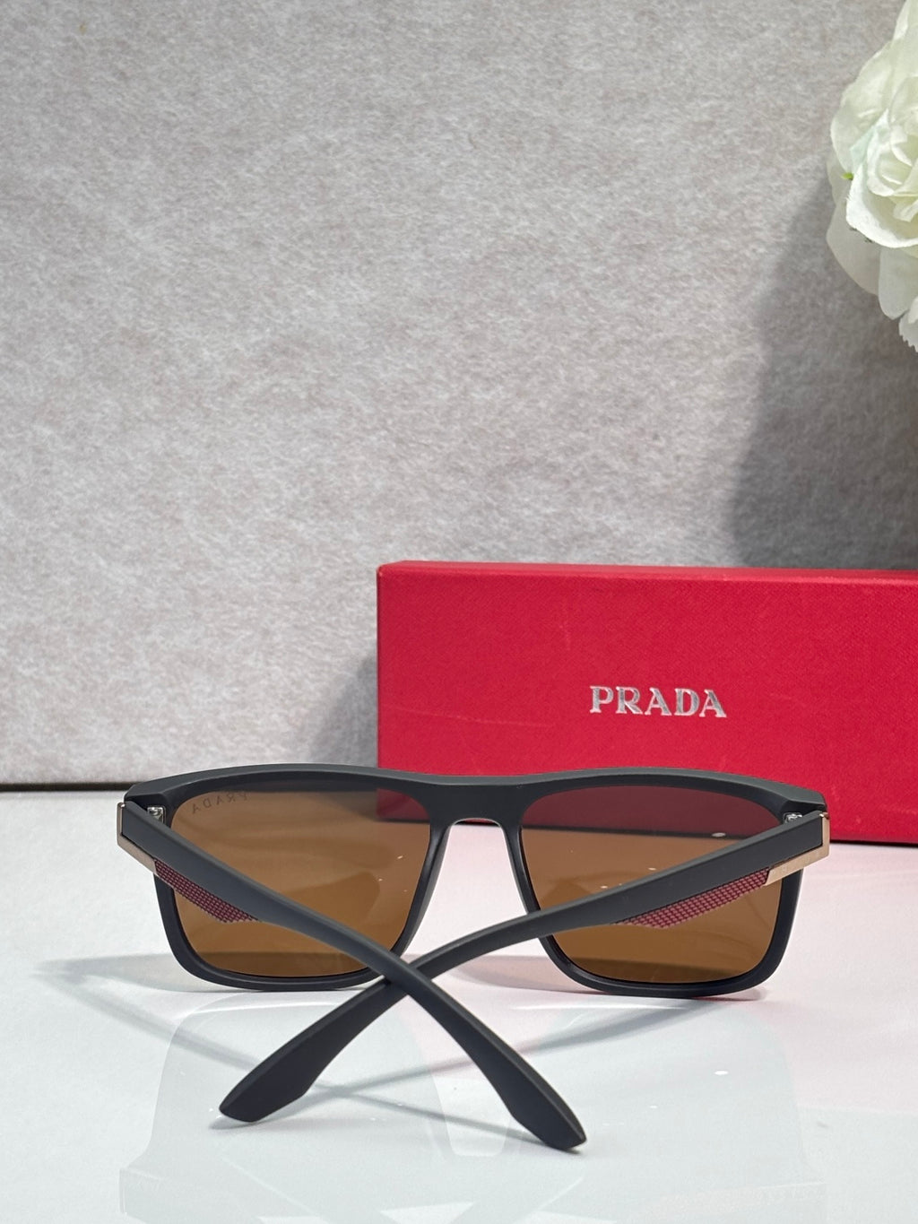 Prada sunglasses with dark frame and warm brown gradient lenses, arched bridge