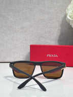 Prada sunglasses with dark frame and warm brown gradient lenses, arched bridge