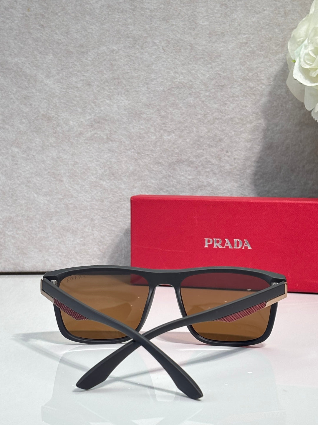 Prada sunglasses with dark frame and warm brown gradient lenses, arched bridge