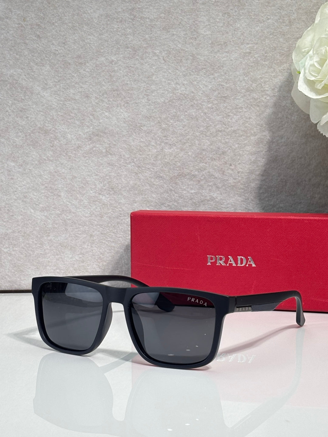 Prada sunglasses with dark navy frames, wide rectangular lenses, and Prada logo temple
