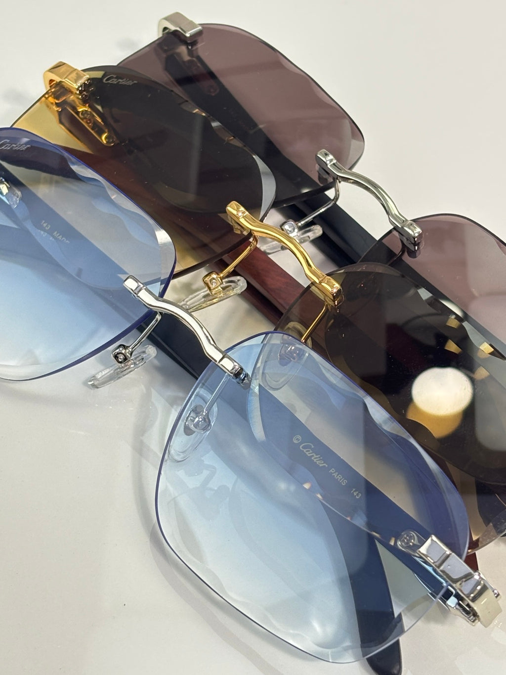 Burgundy-tinted eyeglasses with gold-tone frame and clear blue-tinted pair