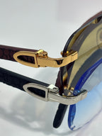 Gold and silver eyeglasses hinge with dark patterned temples and tinted lenses