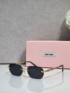 MiuMiu sunglasses with gold metal frame, dark lenses, and embellished temple bar