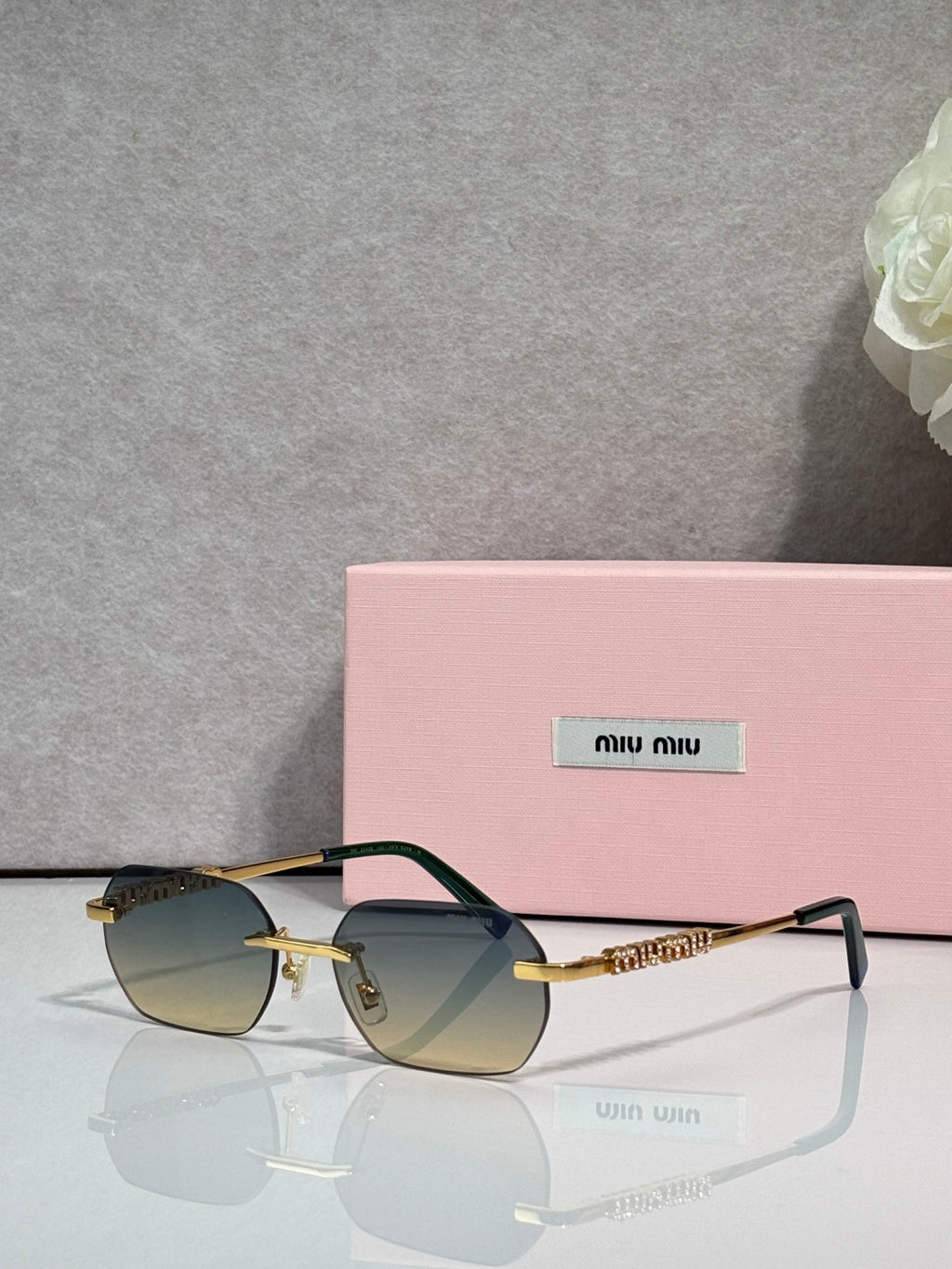 MiuMiu sunglasses with gold metal frame, dark lenses, and jeweled temple detail