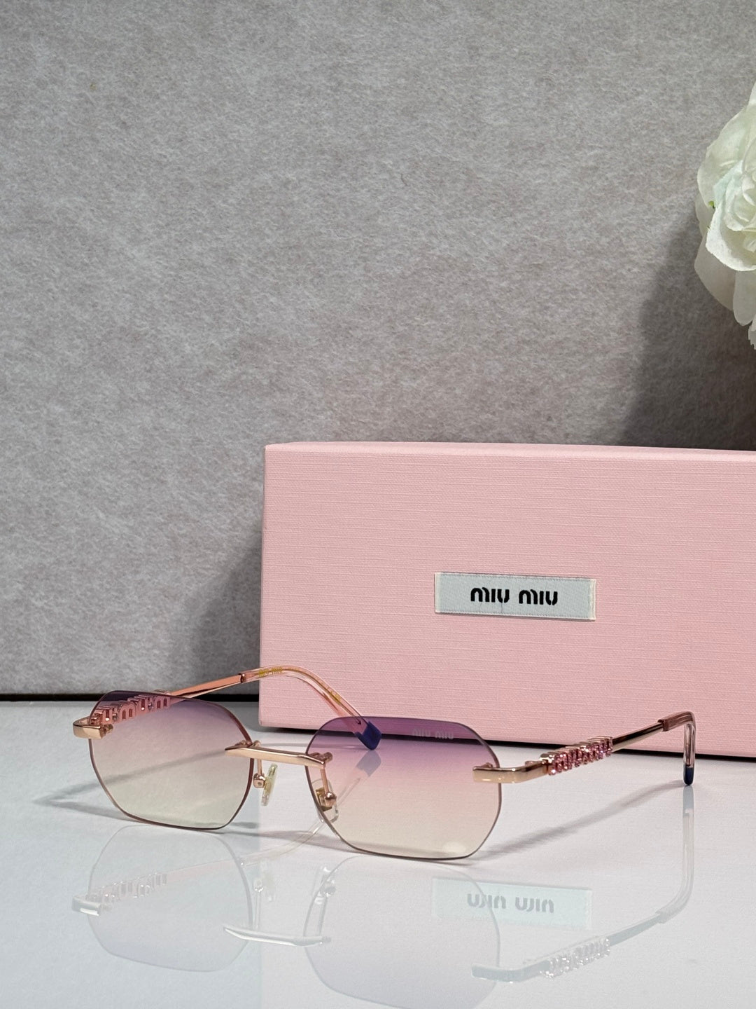 MiuMiu sunglasses with gold metal frame, clear lenses, and jeweled temple detail