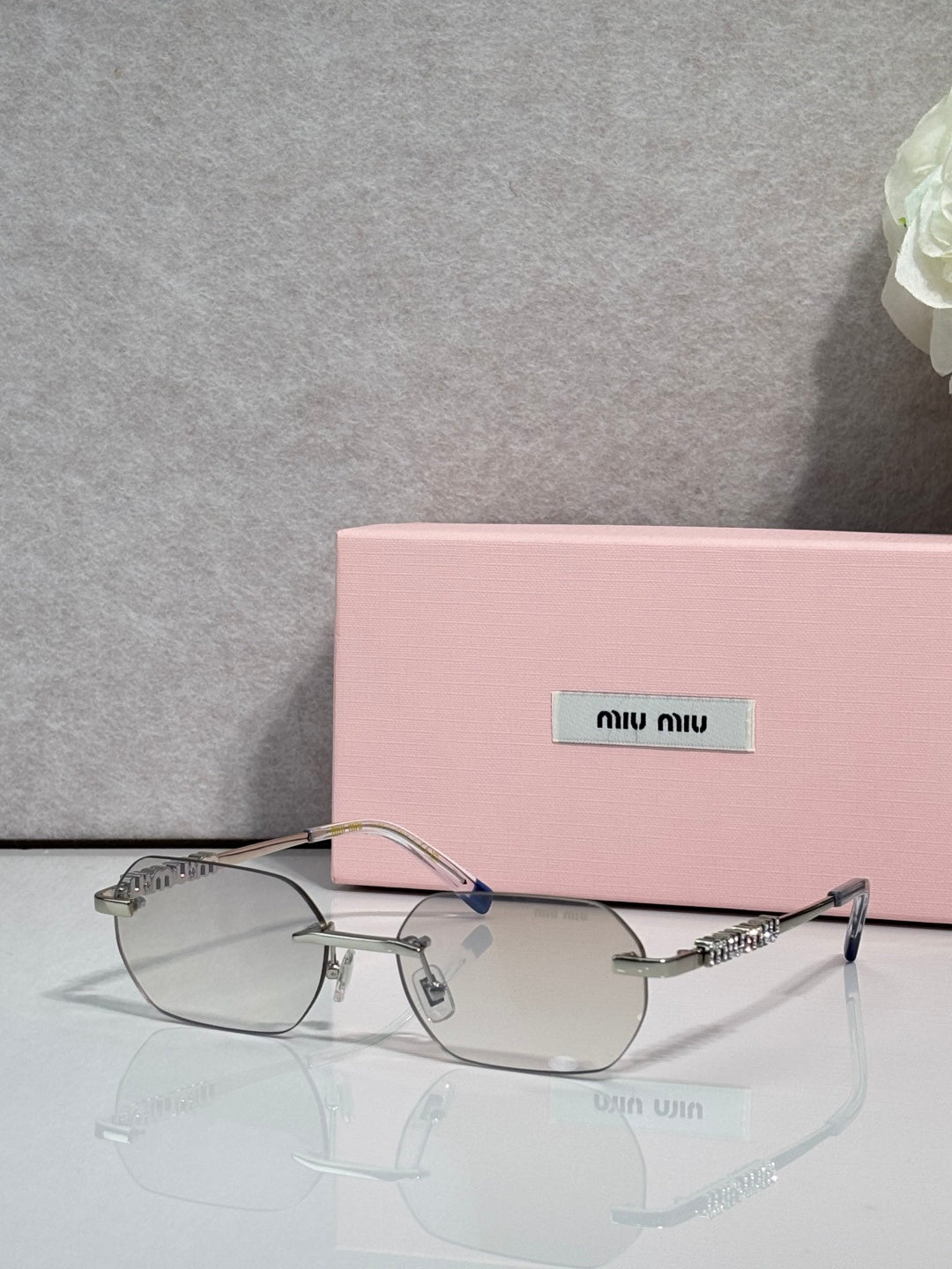 MiuMiu sunglasses with silver metal frame, clear lenses, and jeweled temple detail