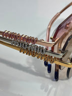 MiuMiu sunglasses close-up: gold-tone temple with jeweled stud row and curved frame