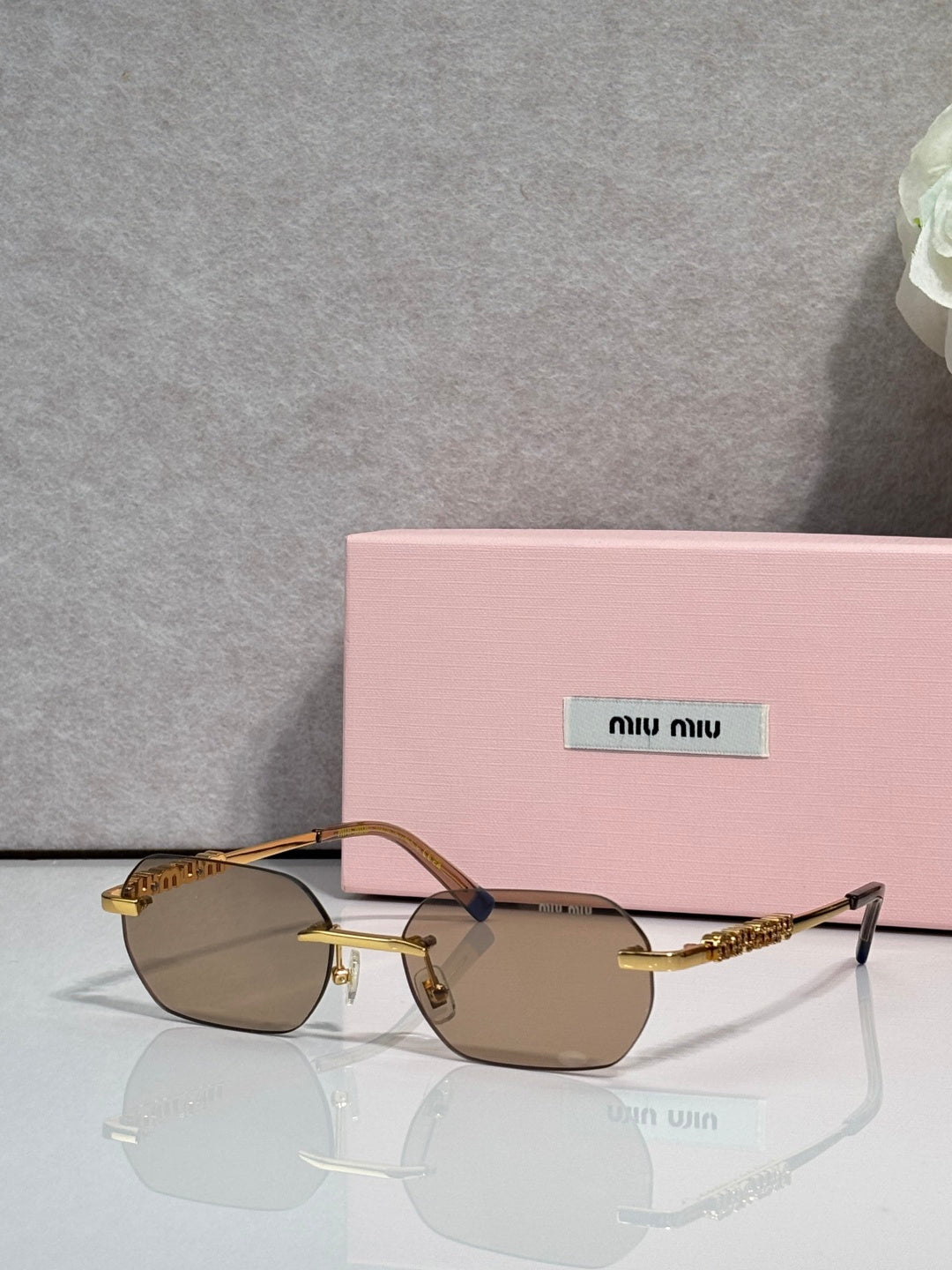 MiuMiu sunglasses with gold metal frame, dark lenses, and jeweled temple detail