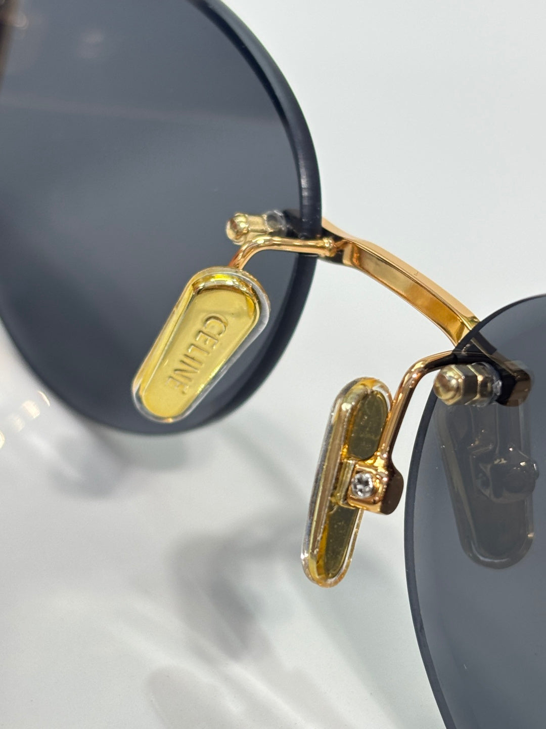 Gold-tone hinge detail on dark round sunglasses with black temple tips