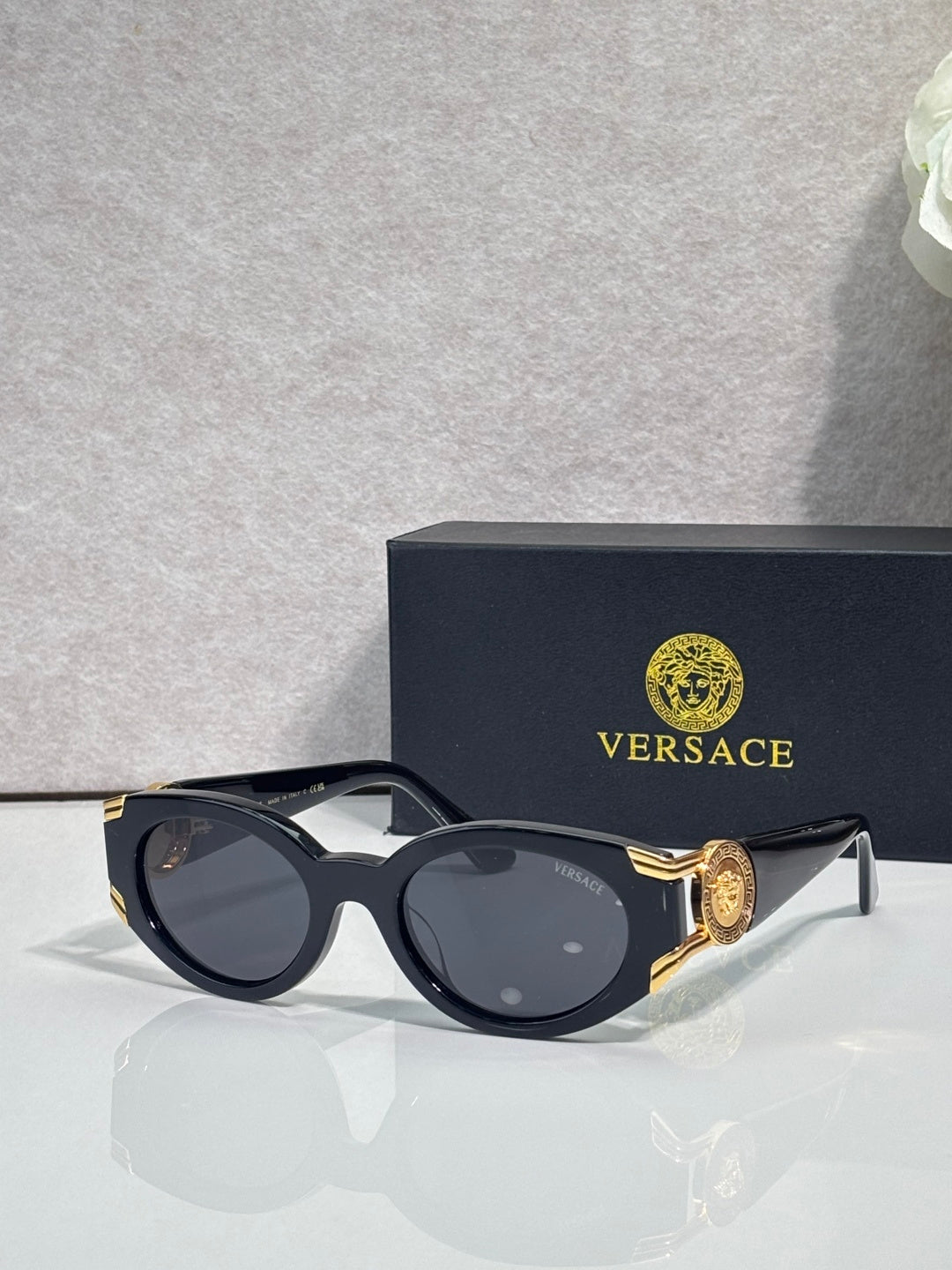 Versace glasses with black oval frames, tinted lenses, gold-tone accents on temples