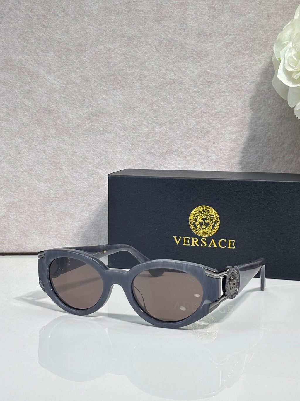 Versace glasses with dark frames, tinted lenses, ornate emblem on temple