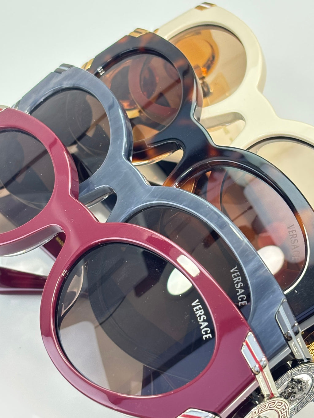 Versace glasses set with pink, blue, and gold frames, round lenses and emblems