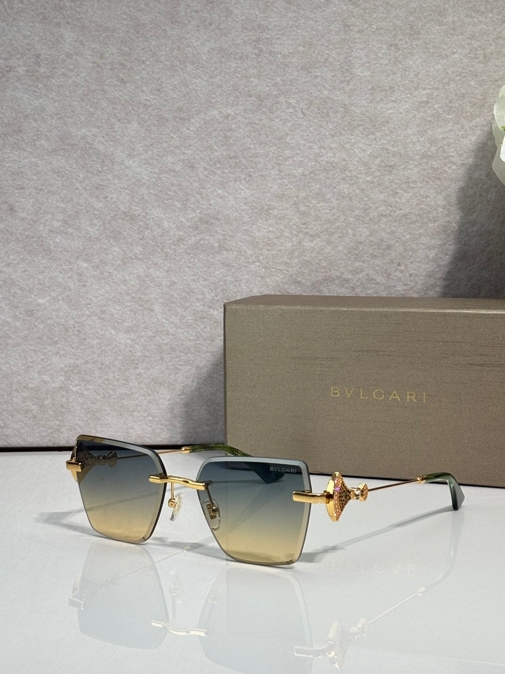 Gold-framed rectangular sunglasses with blue gradient lenses and butterfly bridge charm