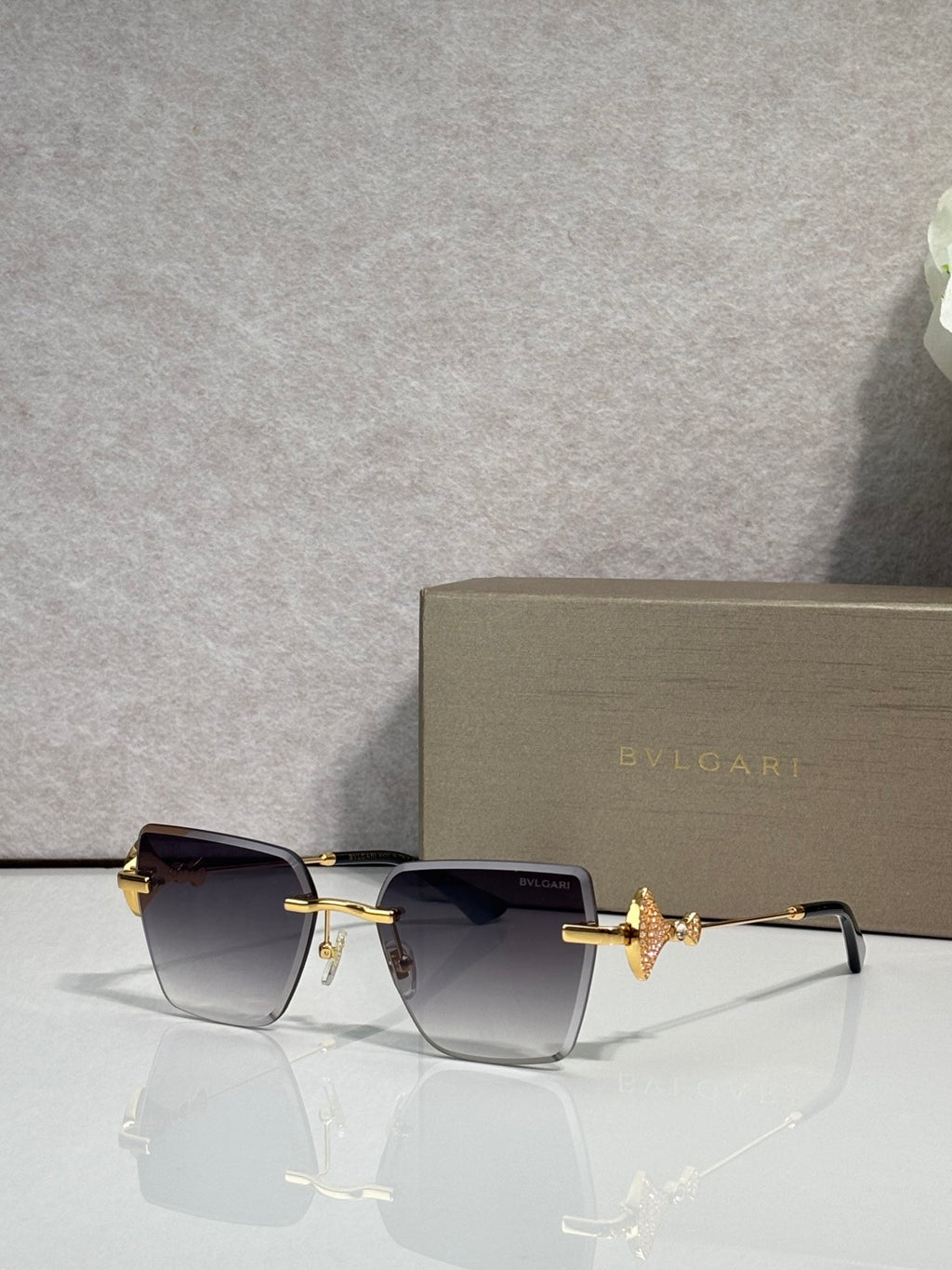 Gold-framed rectangular sunglasses with dark gradient lenses and butterfly bridge charm