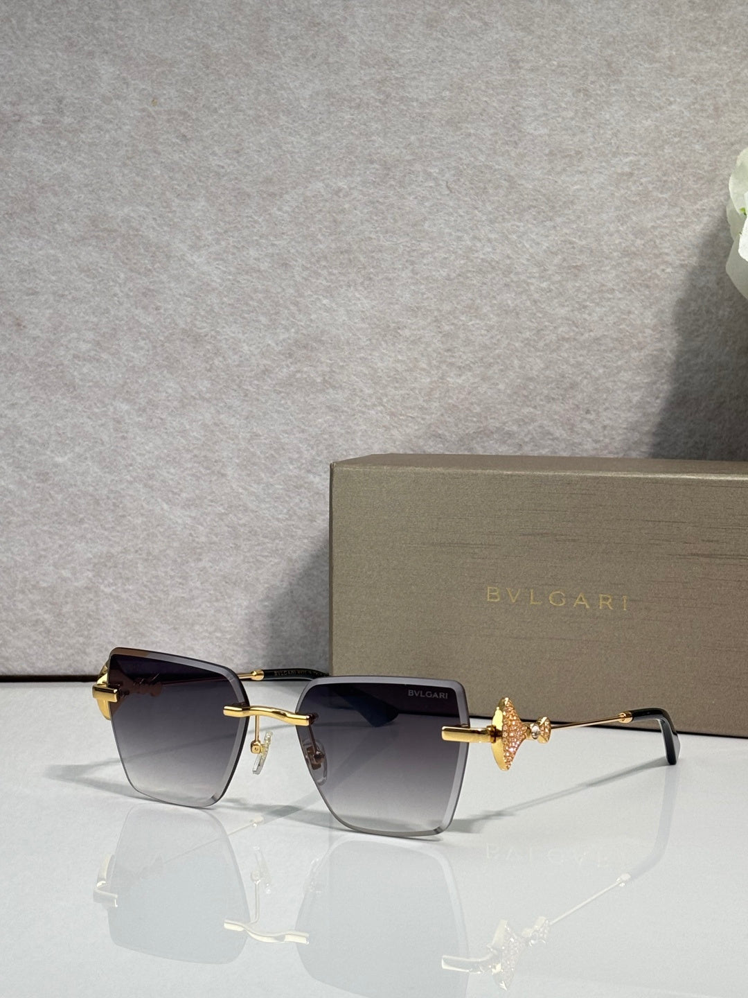 Gold-framed rectangular sunglasses with dark gradient lenses and butterfly bridge charm