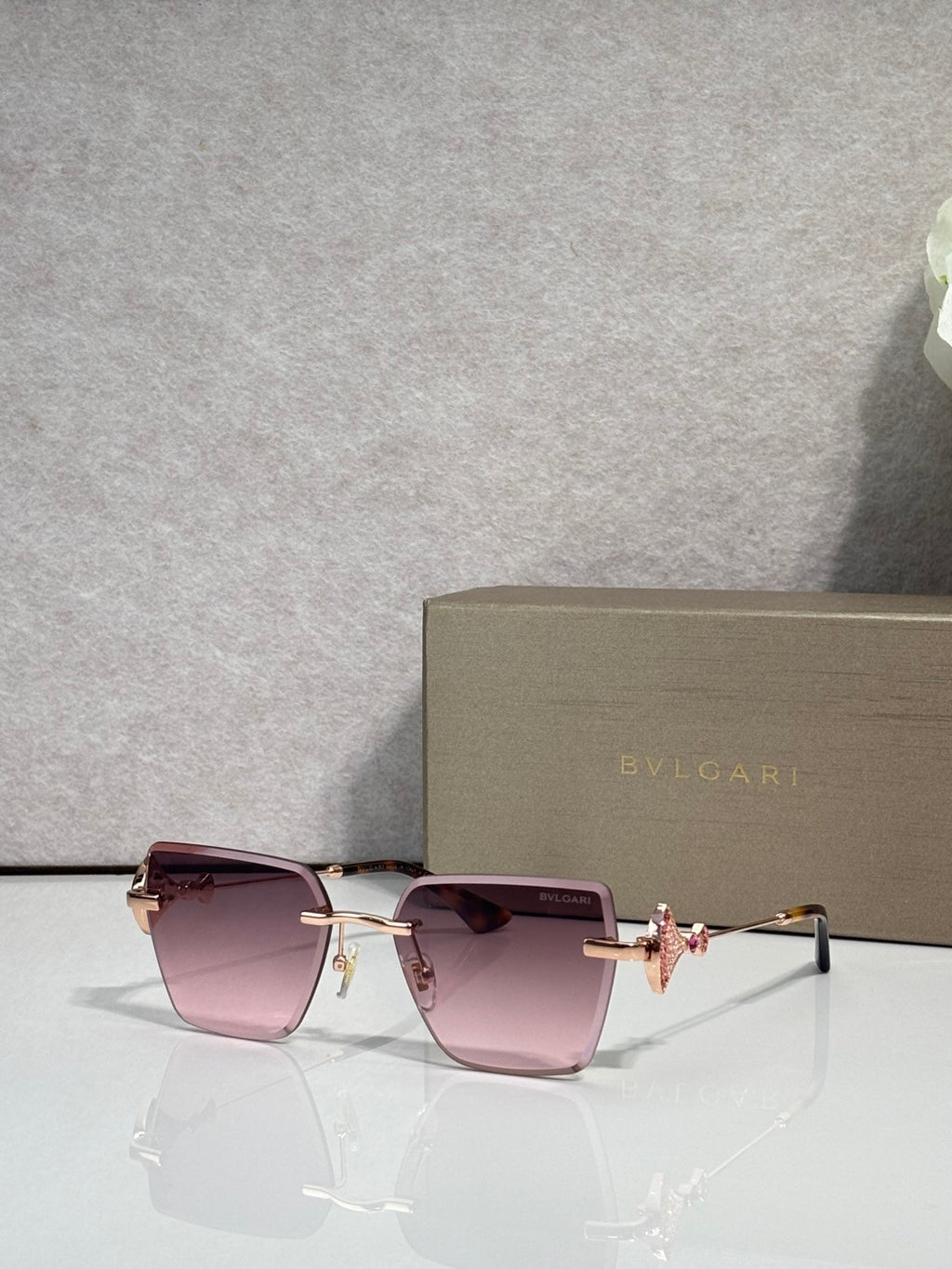 Gold-framed square sunglasses with pink gradient lenses and butterfly bridge charm