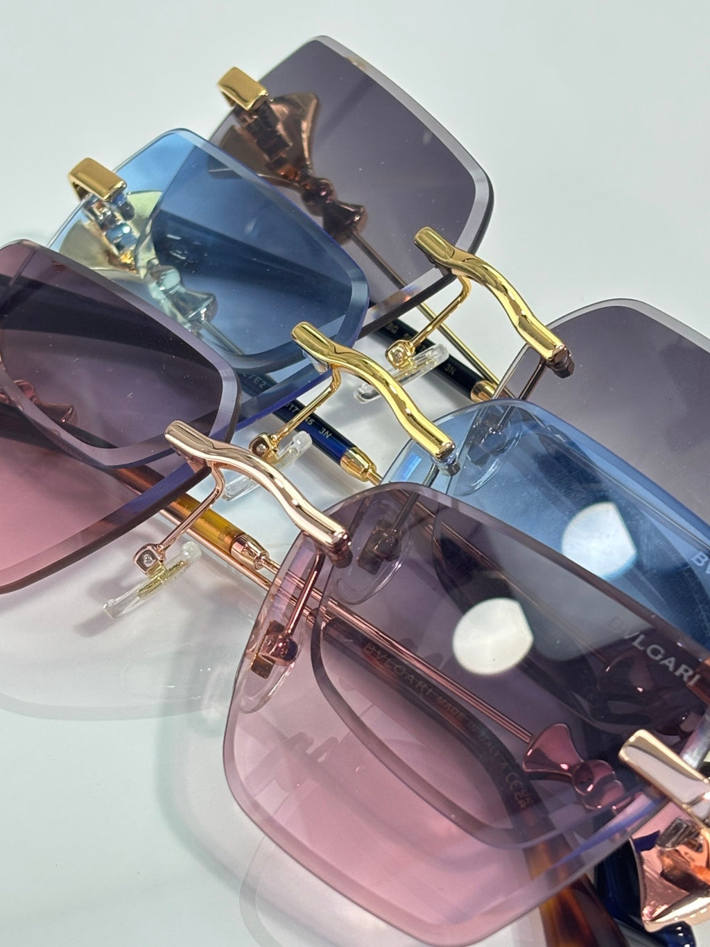 Overlapping gold sunglasses with blue and pink gradient lenses and ornate charms