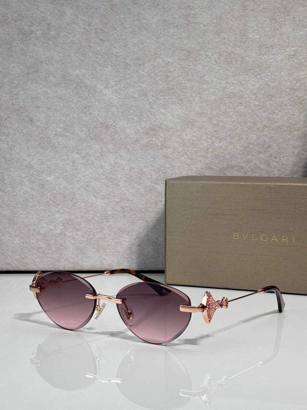 Sunglasses with purple-tinted lenses and gold metal frame, jeweled bow accent