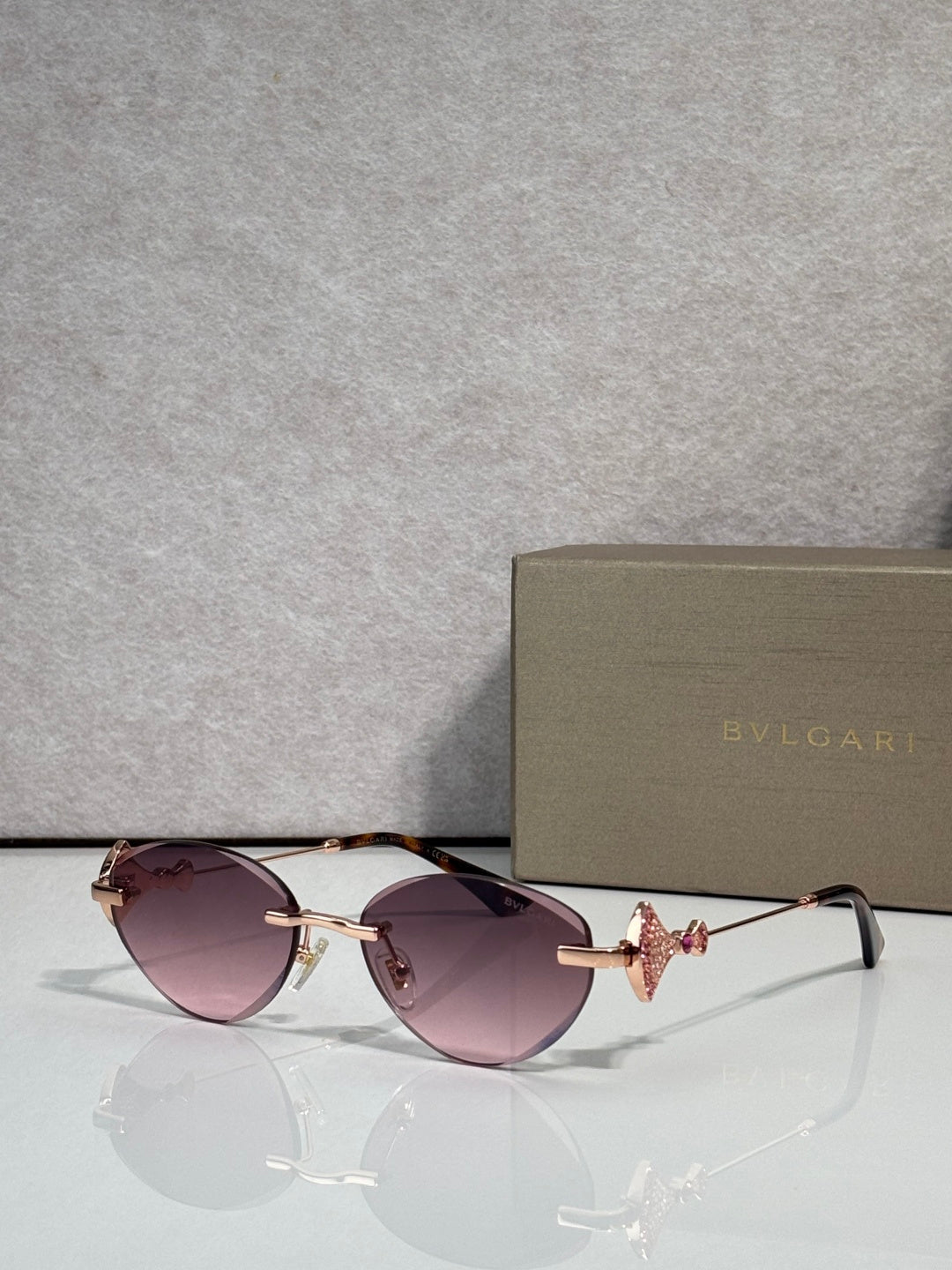 Sunglasses with purple-tinted lenses and gold metal frame, jeweled bow accent