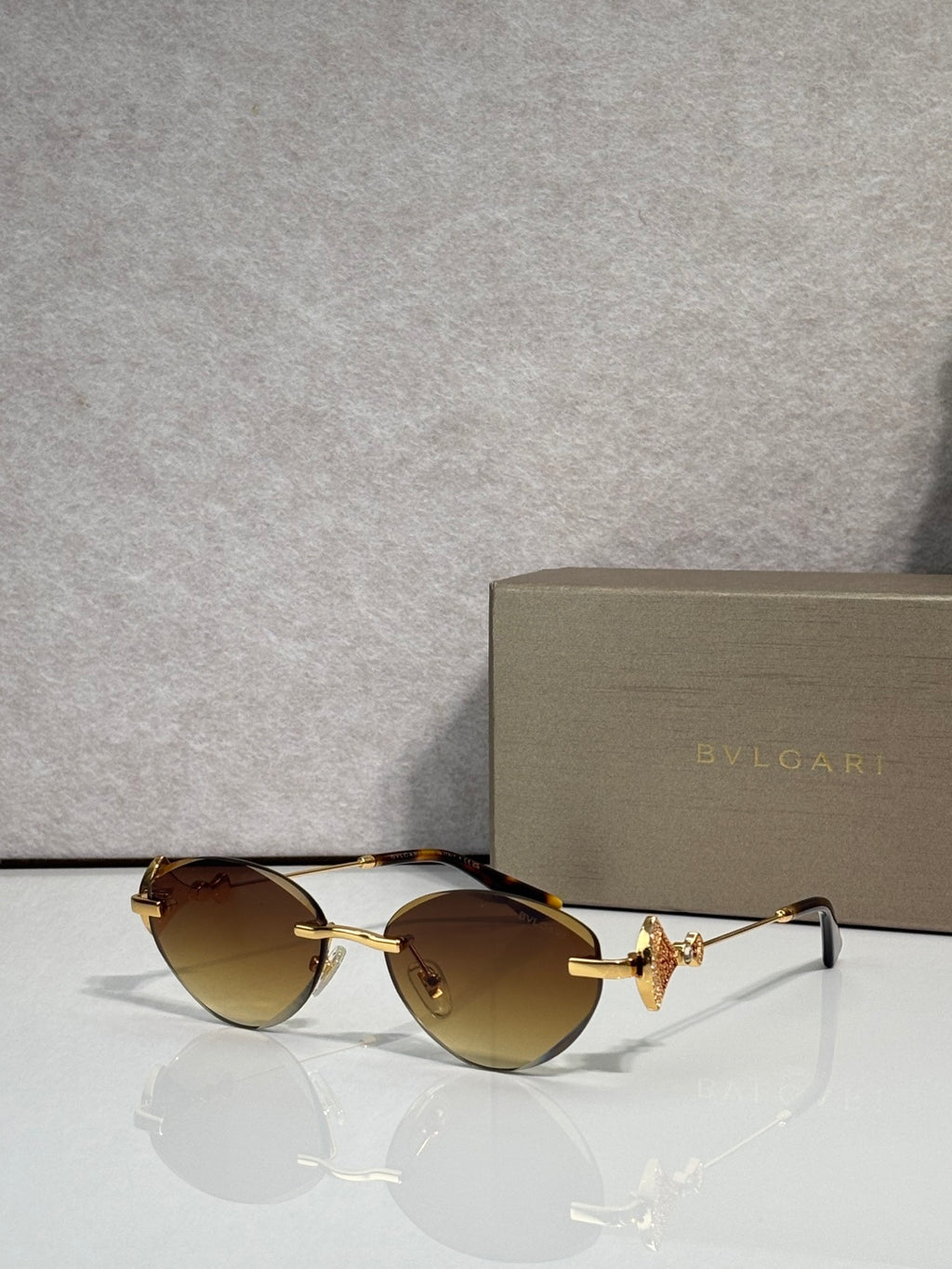 Sunglasses with amber-tinted lenses and gold metal frame, jeweled bow accent