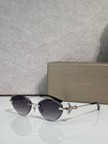 Sunglasses with dark round lenses, black thin metal frame, gold logo detail