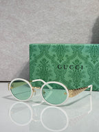 Gucci sunglasses with round white frames, mint lenses, and gold logo at temples