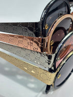 Gucci sunglasses close-up with glossy black and gold frames and embossed logo temples
