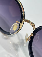 Gucci sunglasses close-up of round dark lens, gold hinge detail, and temple emblem