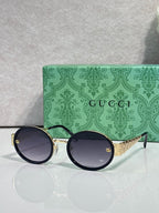 Gucci sunglasses with round black frames and dark lenses, gold logo at temples