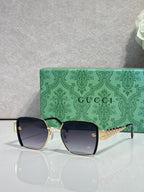 Gucci sunglasses with black frames, green temples, and blue tinted lenses