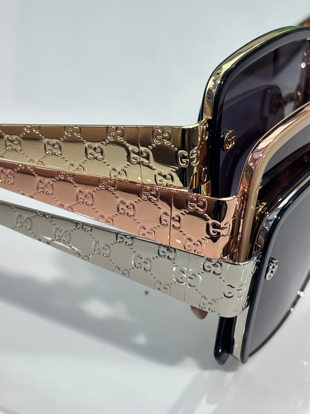 Gucci sunglasses temple close-up with embossed logo pattern and gold finish
