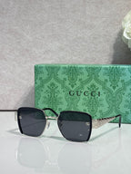 Gucci sunglasses with dark frames, green temples, and tinted lenses