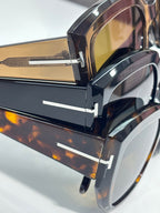 Close-up of tortoiseshell sunglasses with gold-tinted lenses and metal hinge hardware